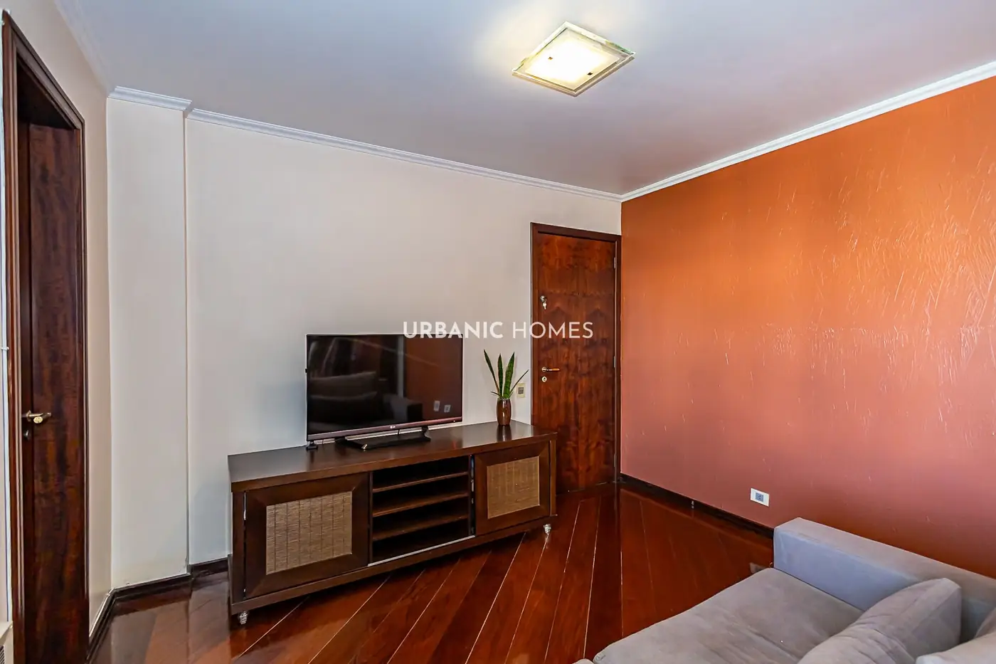 Sala com a TV e a parede laranja
