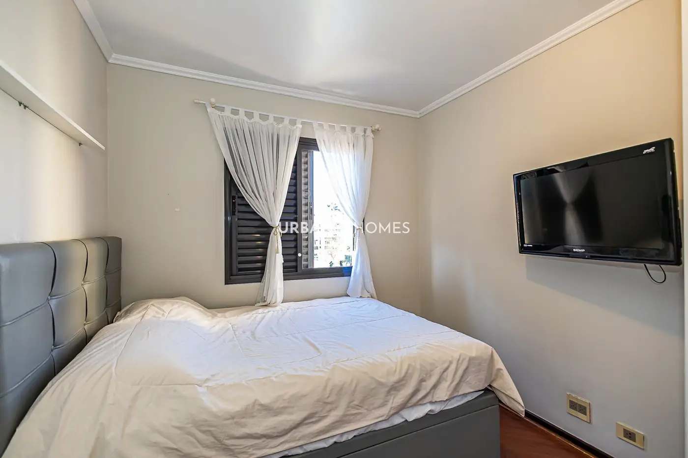 Quarto com TV na parede e janela